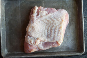 A turkey breast laid out on a baking sheet.