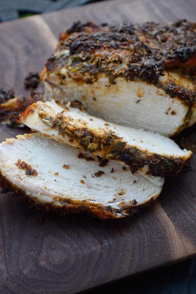 A partially carved Herb-Infused Mediterranean Turkey Breast laying on a cutting board for your Mediterranean Diet Thanksgiving Menu