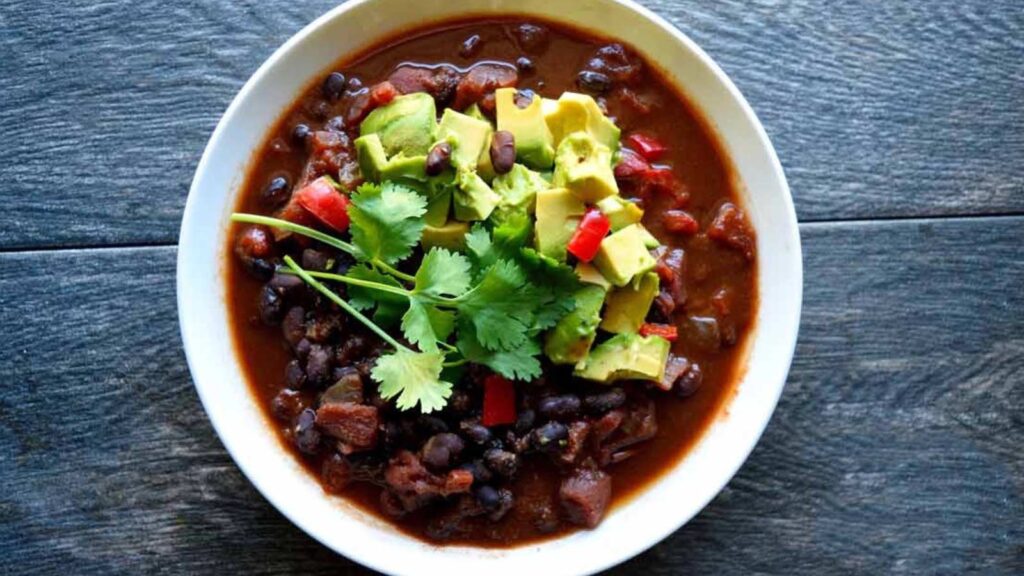 An overhead view of a white bowl filled with Mexican black bean chili.