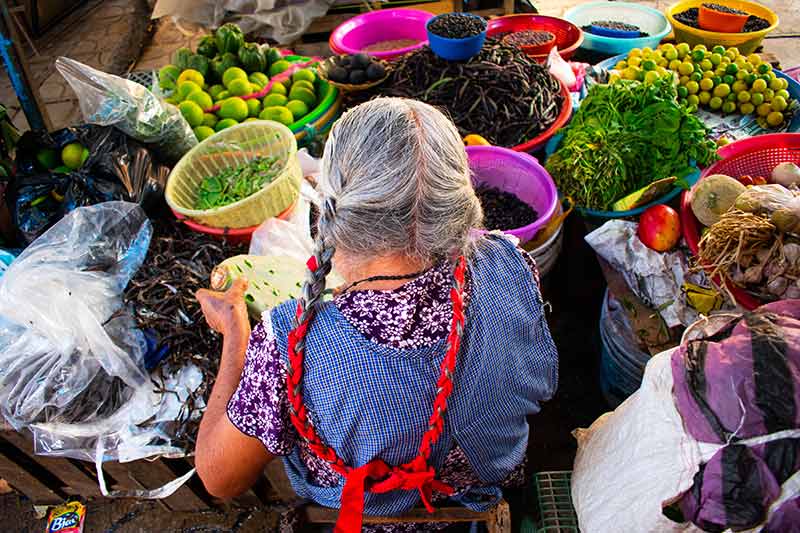 An older woman selling vegetables at a stall in Mexico city.