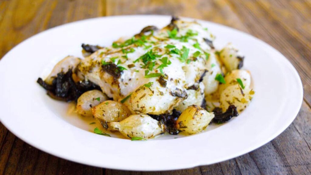 Sheet Pan Mushroom And Onion Cod on a white plate.