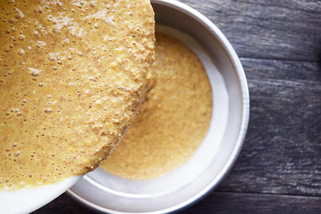 Pouring batter into the lined cake pan.