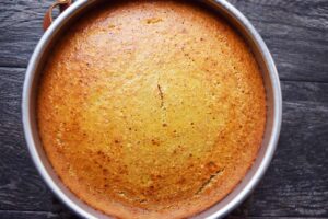 Just baked Orange Almond Cake in a cake pan. The top is golden brown.