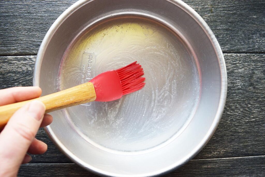 Brushing a cake pan with oil.