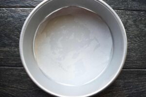 Parchment lining the bottom of an 8-inch round cake pan.