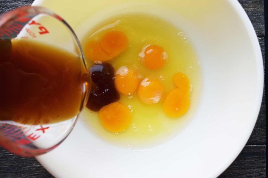 Combining wet ingredients in a mixing bowl, including eggs.