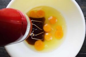 An electric mixer in the bowl of wet ingredients.