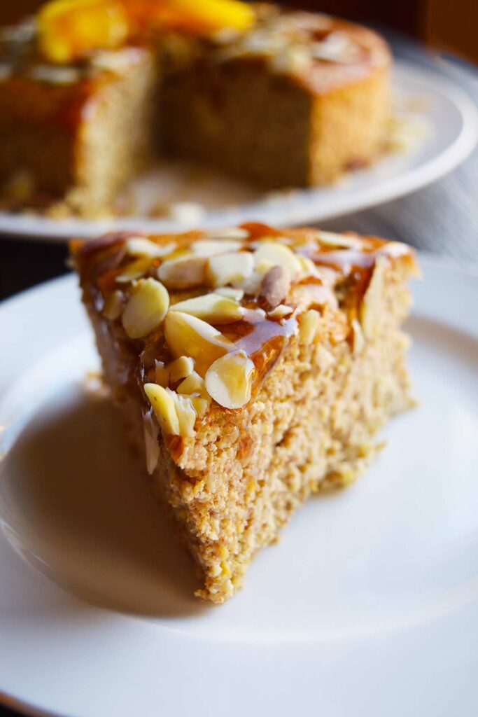 A slice of Orange Almond Cake on a white plate.