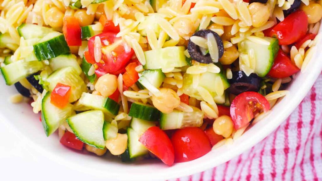 A white bowl filled with chickpea orzo salad.