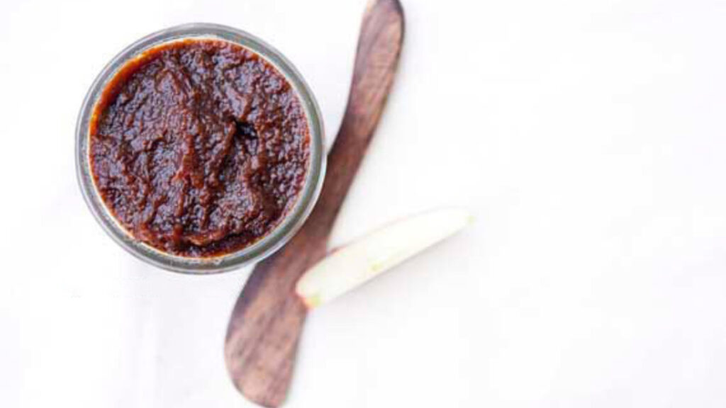 An open jar filled with Overnight Apple Butter on a white background.