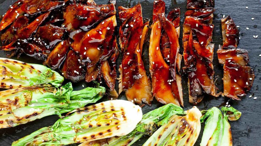 Oyster mushroom steak, sliced and laying on a slate board.