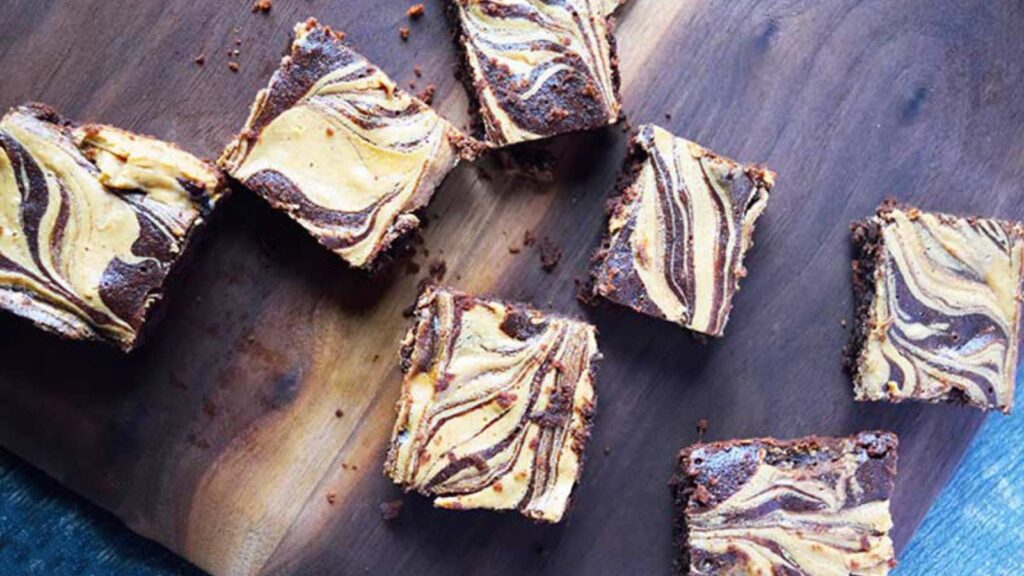 Several Homemade Peanut Butter Swirl Brownies spread out on a cutting board.