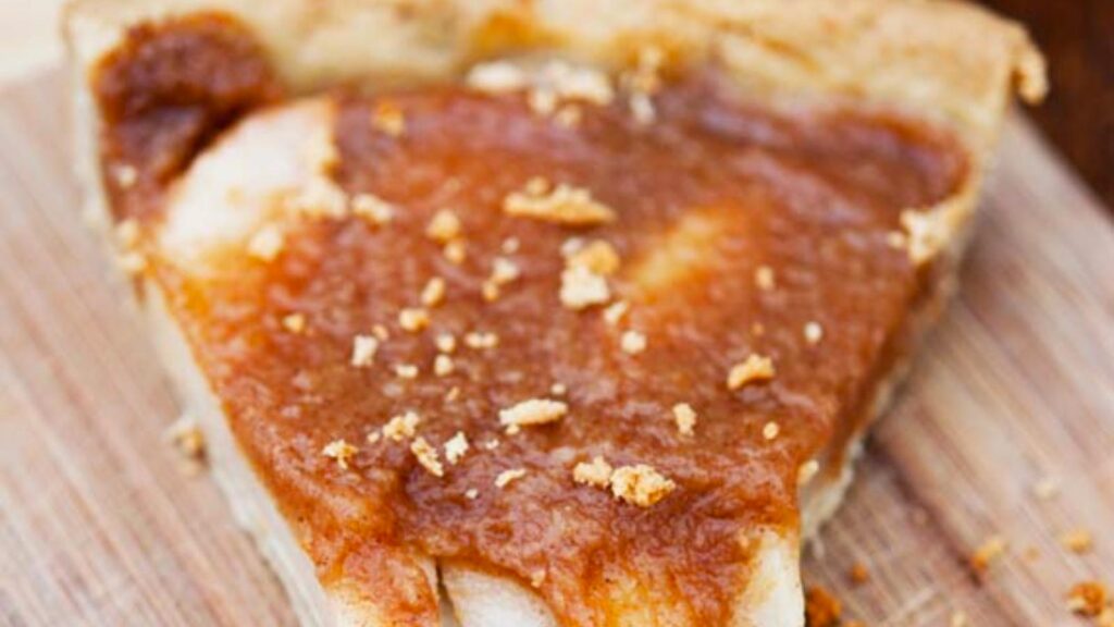 A closeup of a slice of Pear And Apple Tart sitting on a wooden surface.