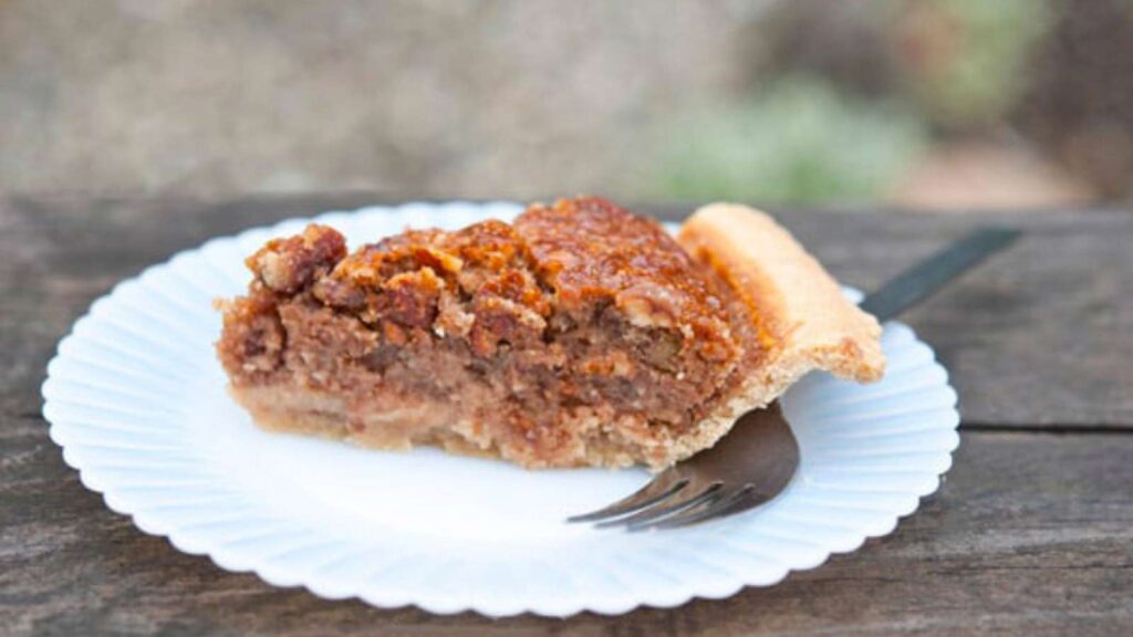 A slice of naturally sweetened pecan pie on a white plate.