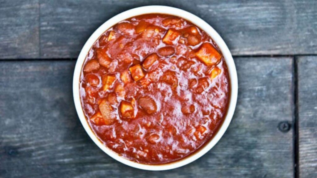 A white bowl filled with pork and beans.