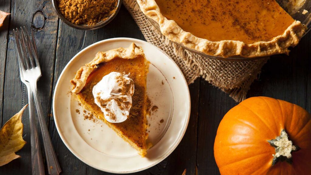 A slice of pumpkin pit next to the pan it was taken from, sitting on a table.