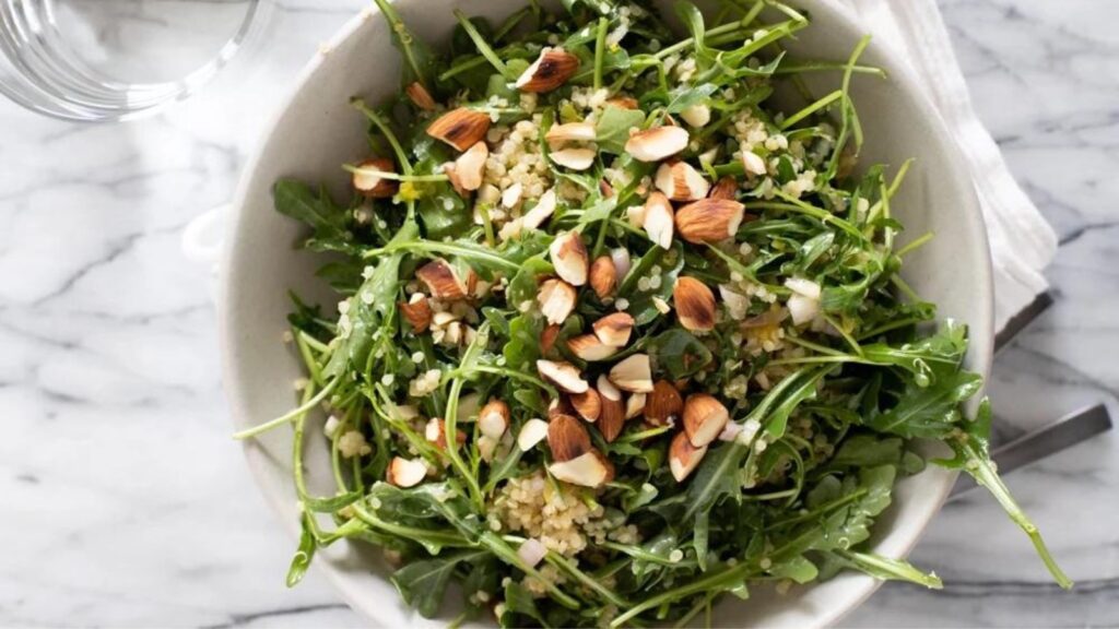 An overhead view of a white ceramic bowl filled with Quinoa Arugula Salad.