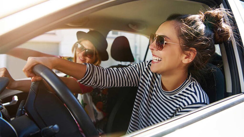 Two young women driving in a car.