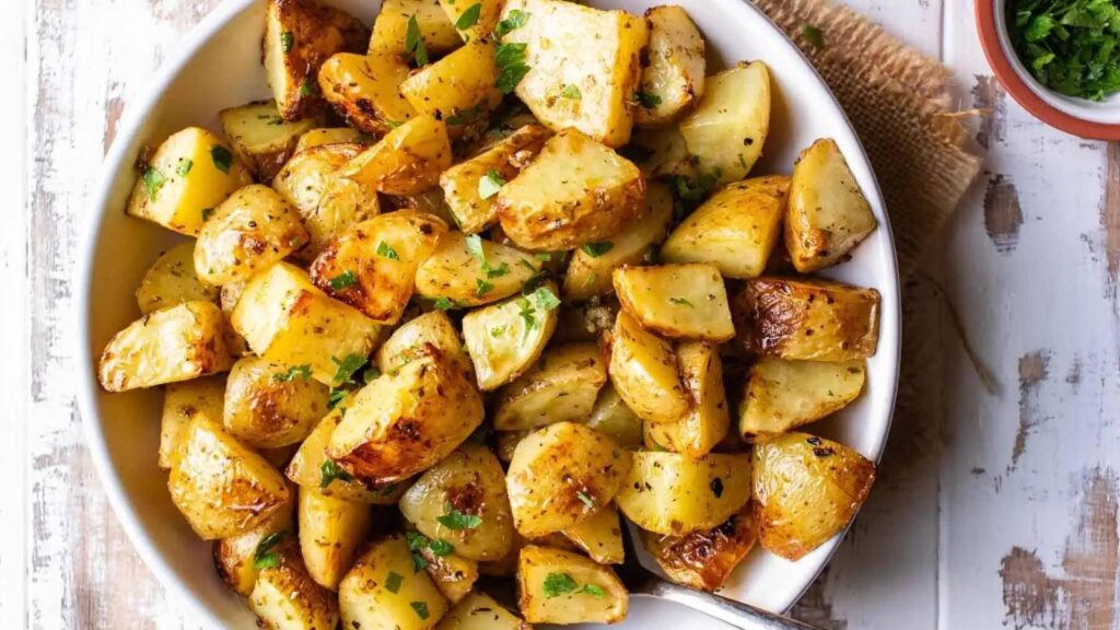 A white bowl filled with roasted Mediterranean potatoes.