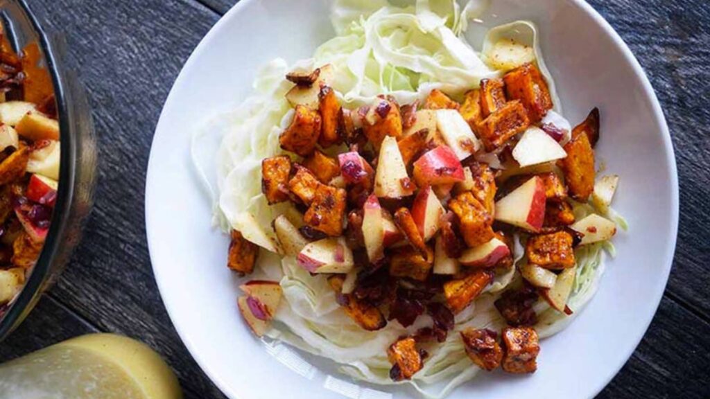 A white bowl filled halfway with roasted sweet potato salad.