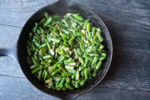 Mixed green beans and sliced almonds with garlic in a skillet.