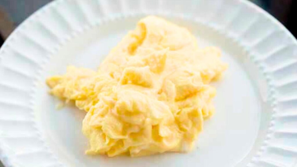 A white plate with scrambled eggs on it.