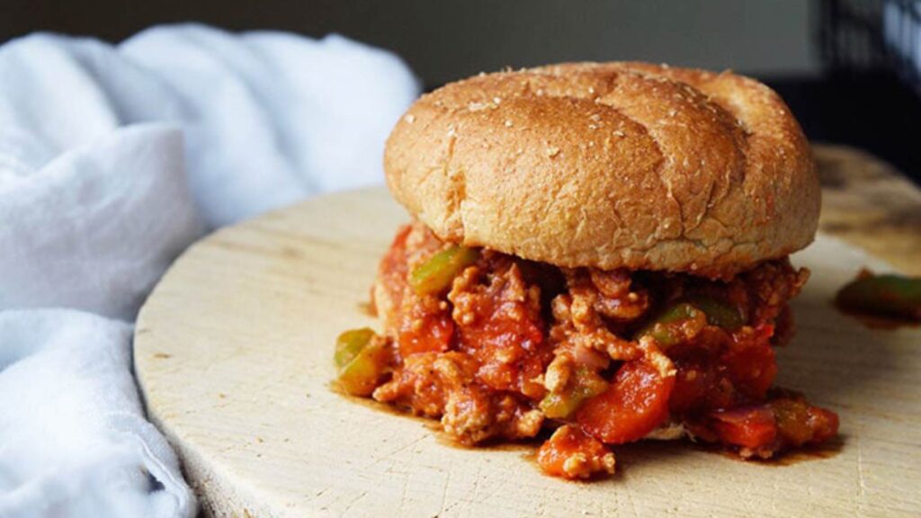 A fully assembled Healthy Turkey Sloppy Joe sits on a cutting board.