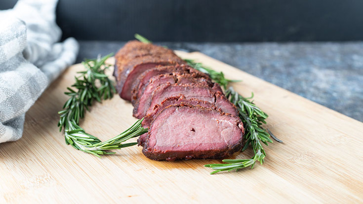 Sliced venison backstrap on a cutting board.