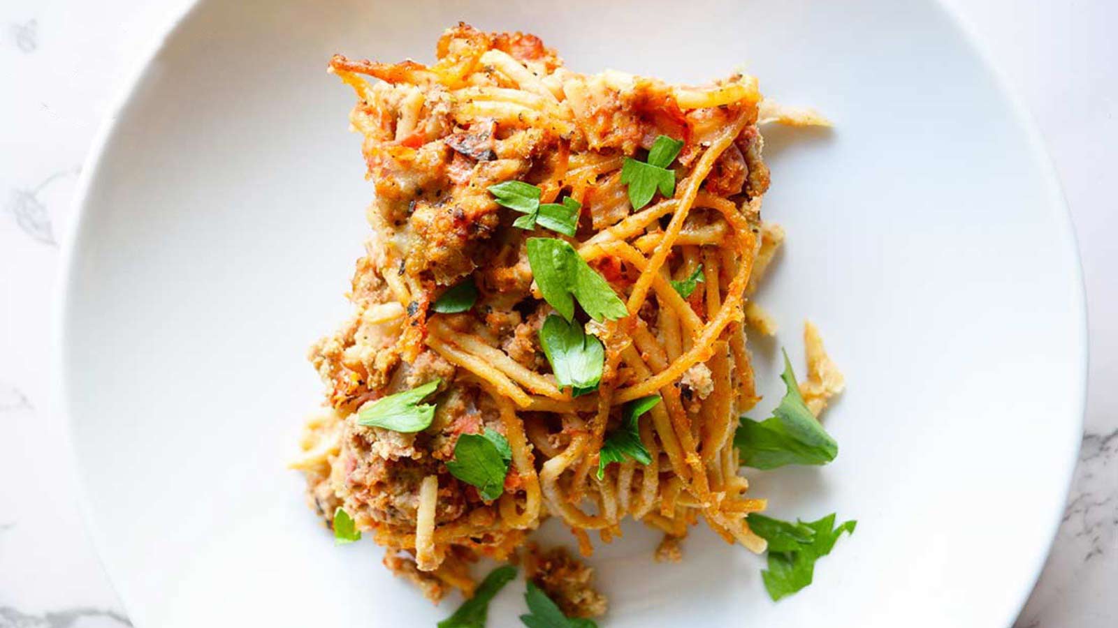 A slice of spaghetti pie in a white bowl.