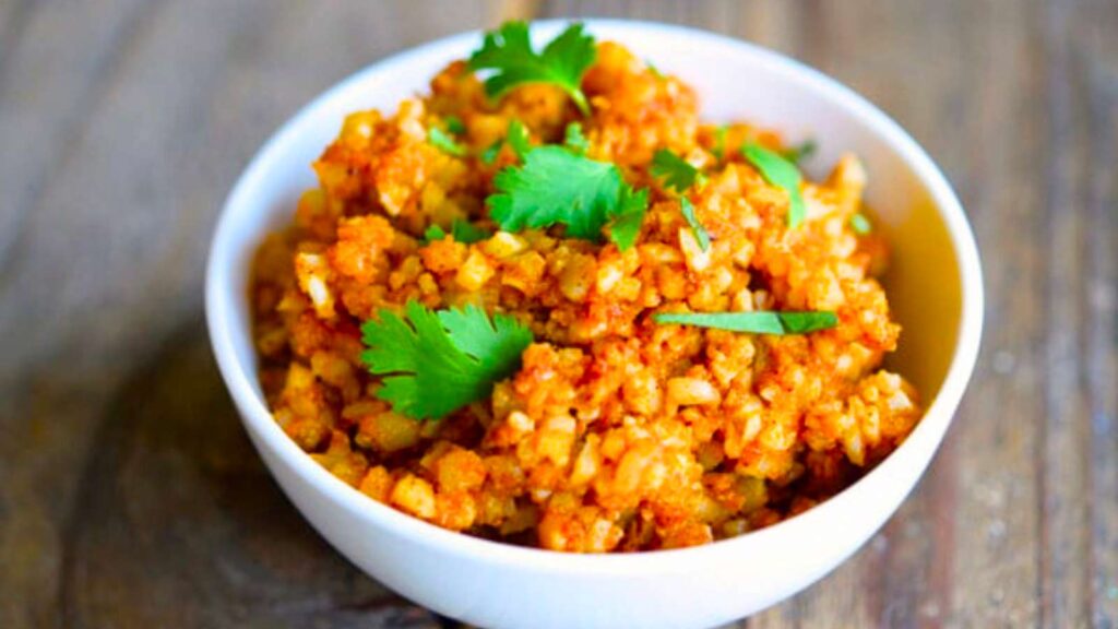 A white bowl filled with Spanish Cauliflower Rice and topped with fresh cilantro leaves.