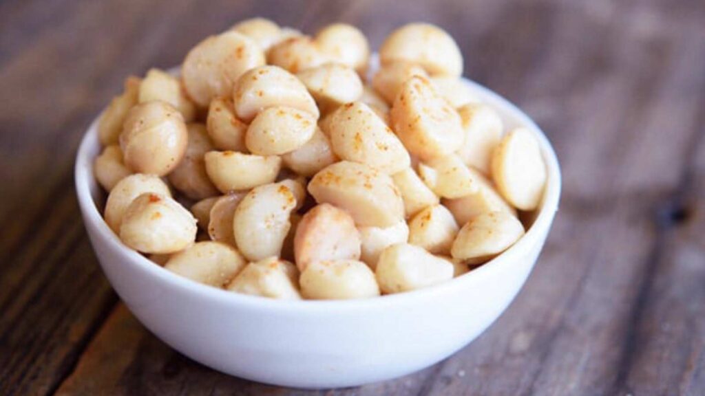 A small white bowl full of Spicy Sweet Macadamia Nuts.