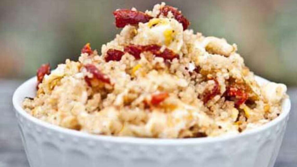 A white bowl filled with Sun-Dried Tomato Breakfast Couscous.