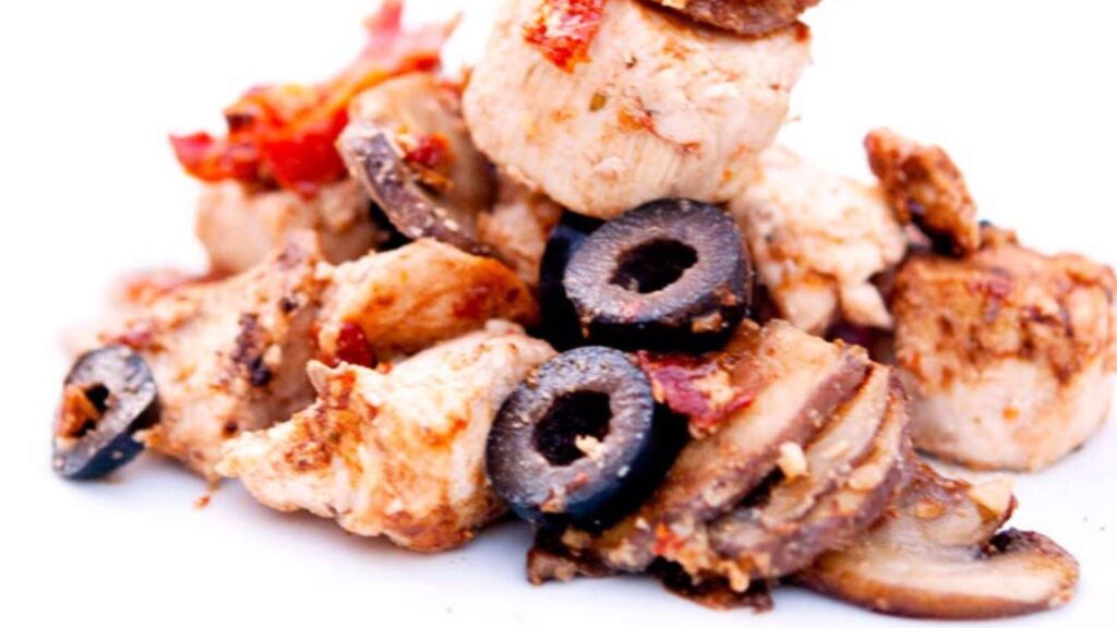 A closeup of Sun Dried Tomato And Olive Chicken on a white plate.
