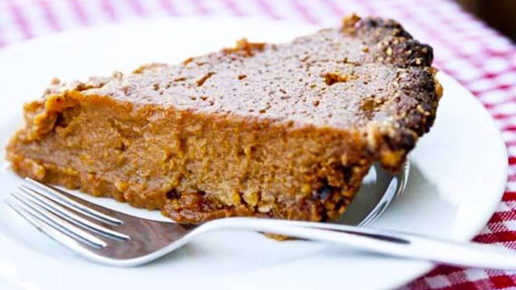 A slice of sweet potato pie on a white plate with a fork.