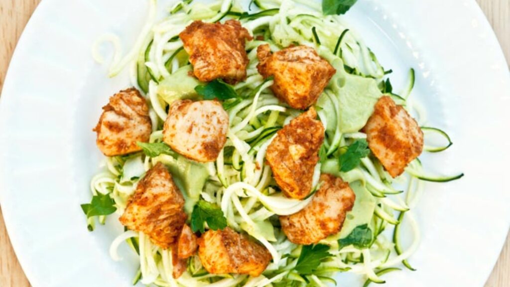 Taco chicken on zucchini noodles, on a white plate, on a table.