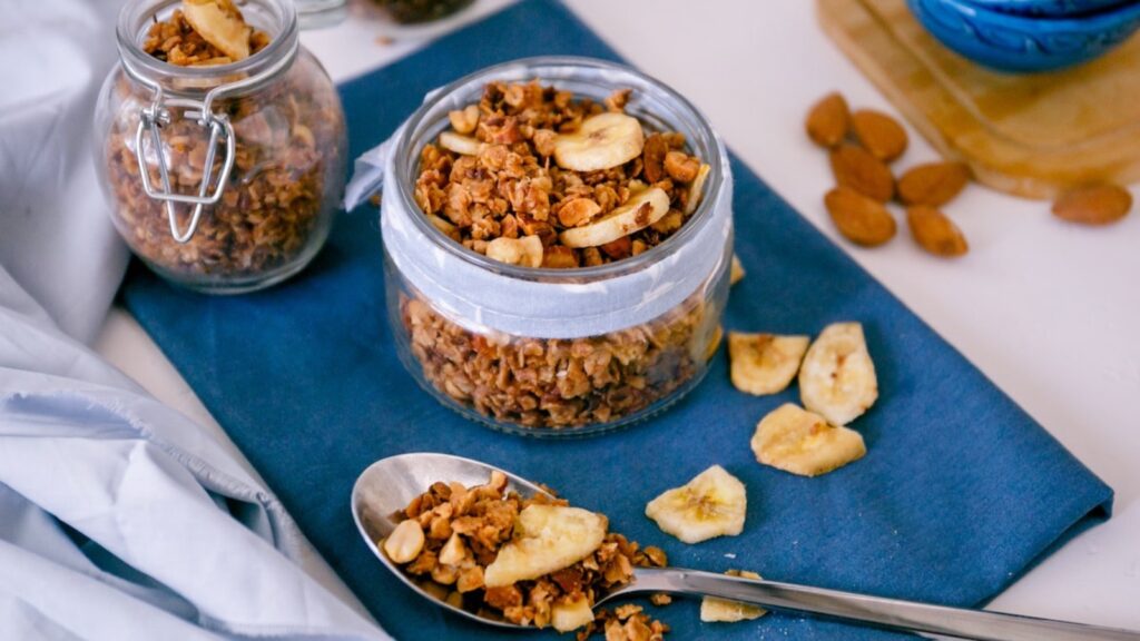 Two jars and spoon filled with banana granola.