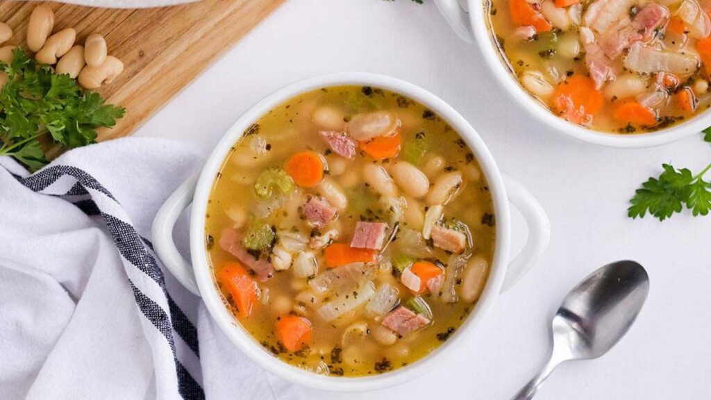 An overhead view of a white crock filled with ham and bean soup.