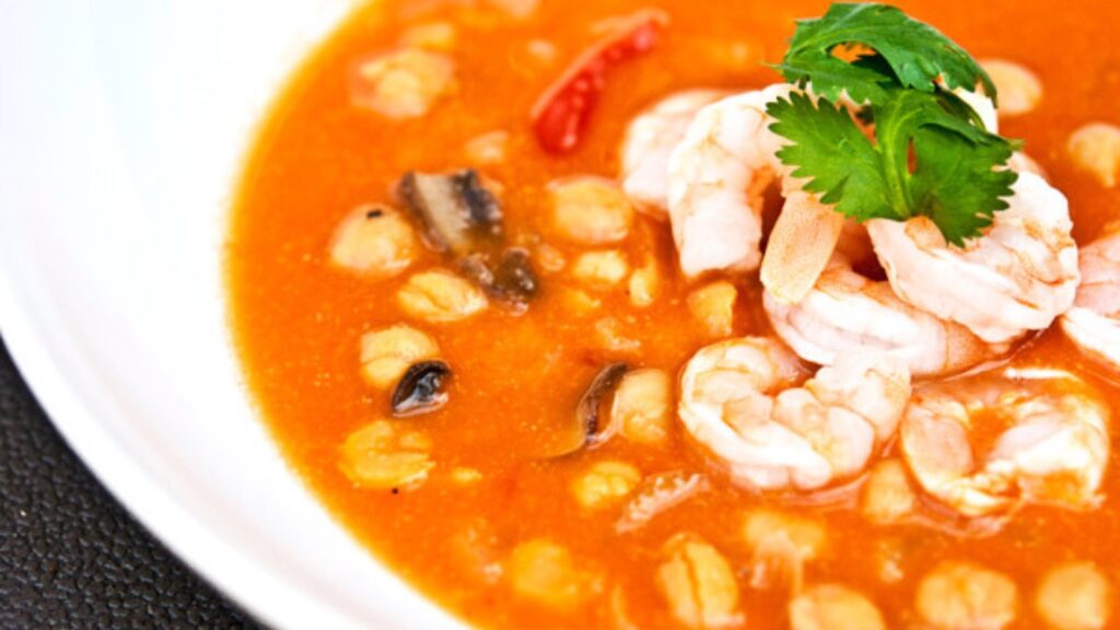 A white bowl filled with Thai shrimp and chickpea soup.