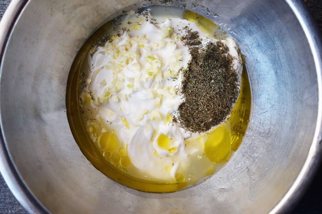 Yogurt, garlic, dill, lemon juice and oil in a mixing bowl.