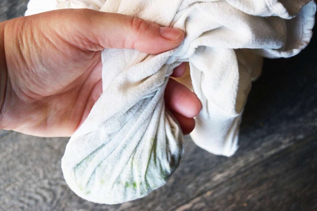 A tea towel filled with grated cucumber, partially wrung out.