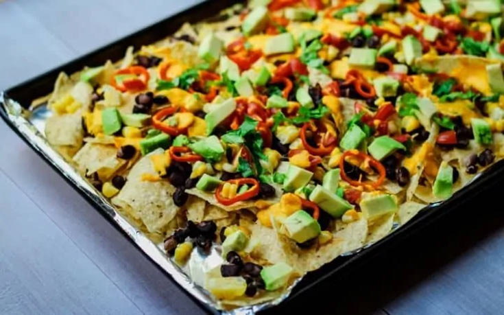A baking sheet of black bean nachos on a wood surface.