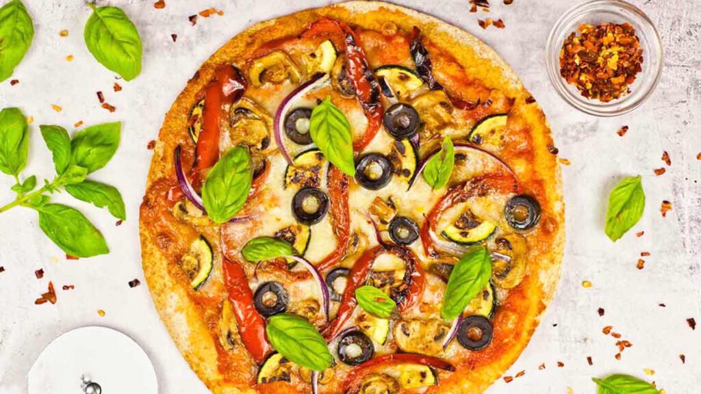 Fresh basil leaves sprinkled over a cooked veggie pizza.