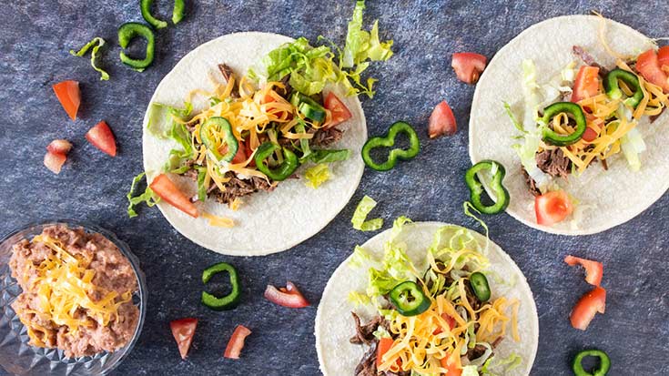 An overhead view of three venison tacos with taco toppings.