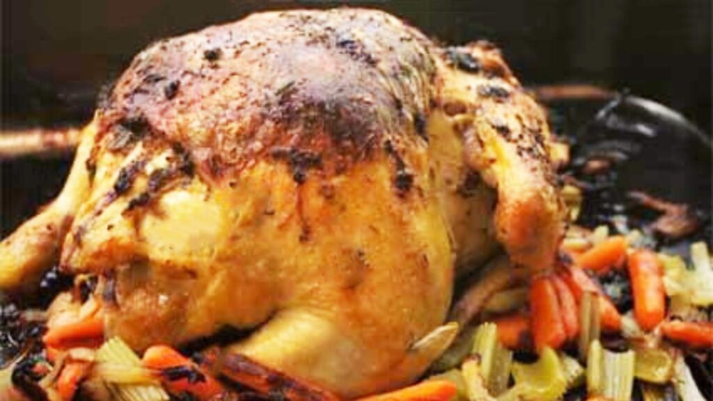A Whole Roasted Chicken in a roasting pan with vegetables.