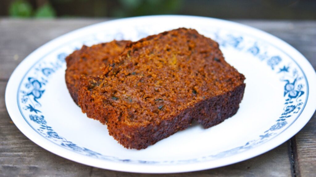 Two slices of zucchini bread lay on a plate.