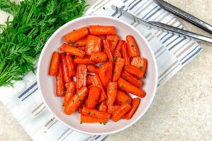 An overhead view of air fryer carrots in a white bowl.