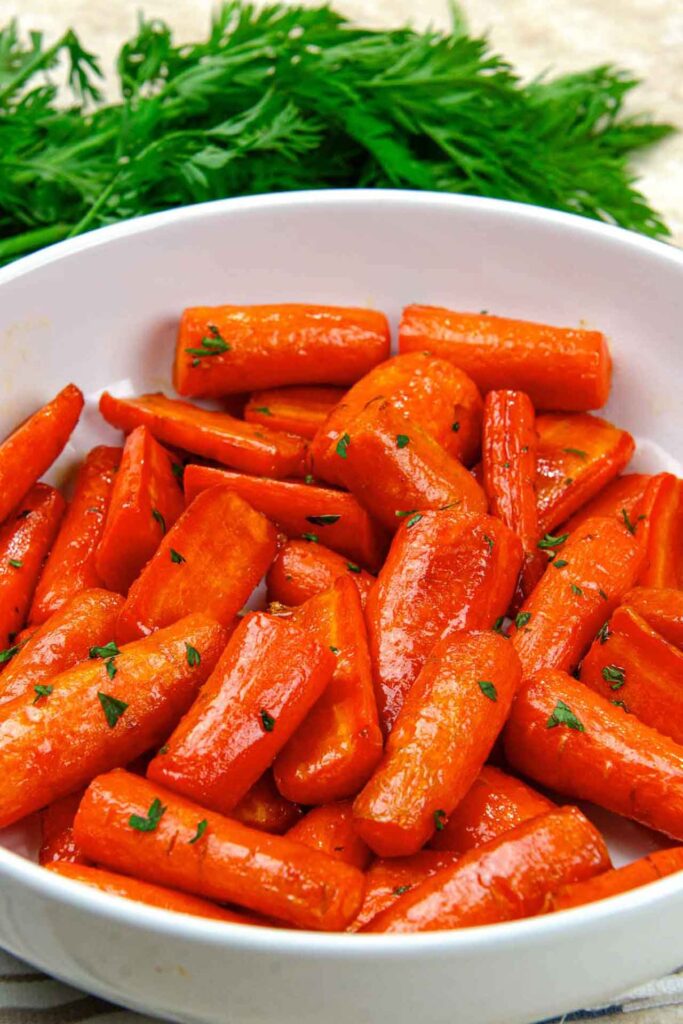 A side view of a white bowl filled with air fryer carrots.