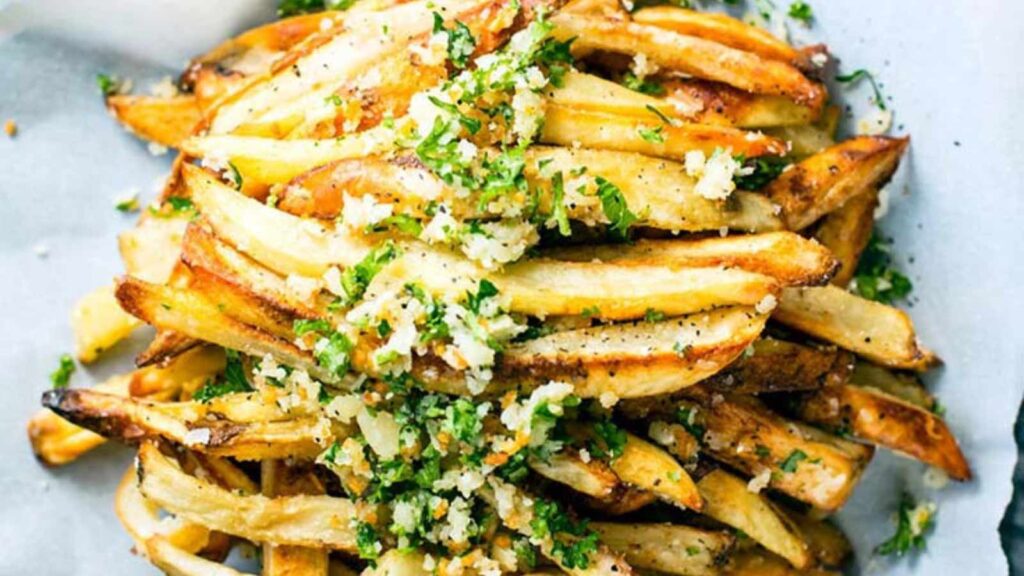 An overhead view of baked parmesan garlic fries on parchment paper.