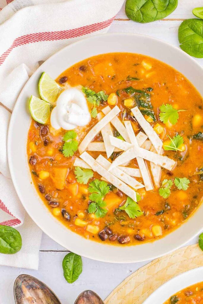 Tortilla soup in a white bowl with some lime slices.