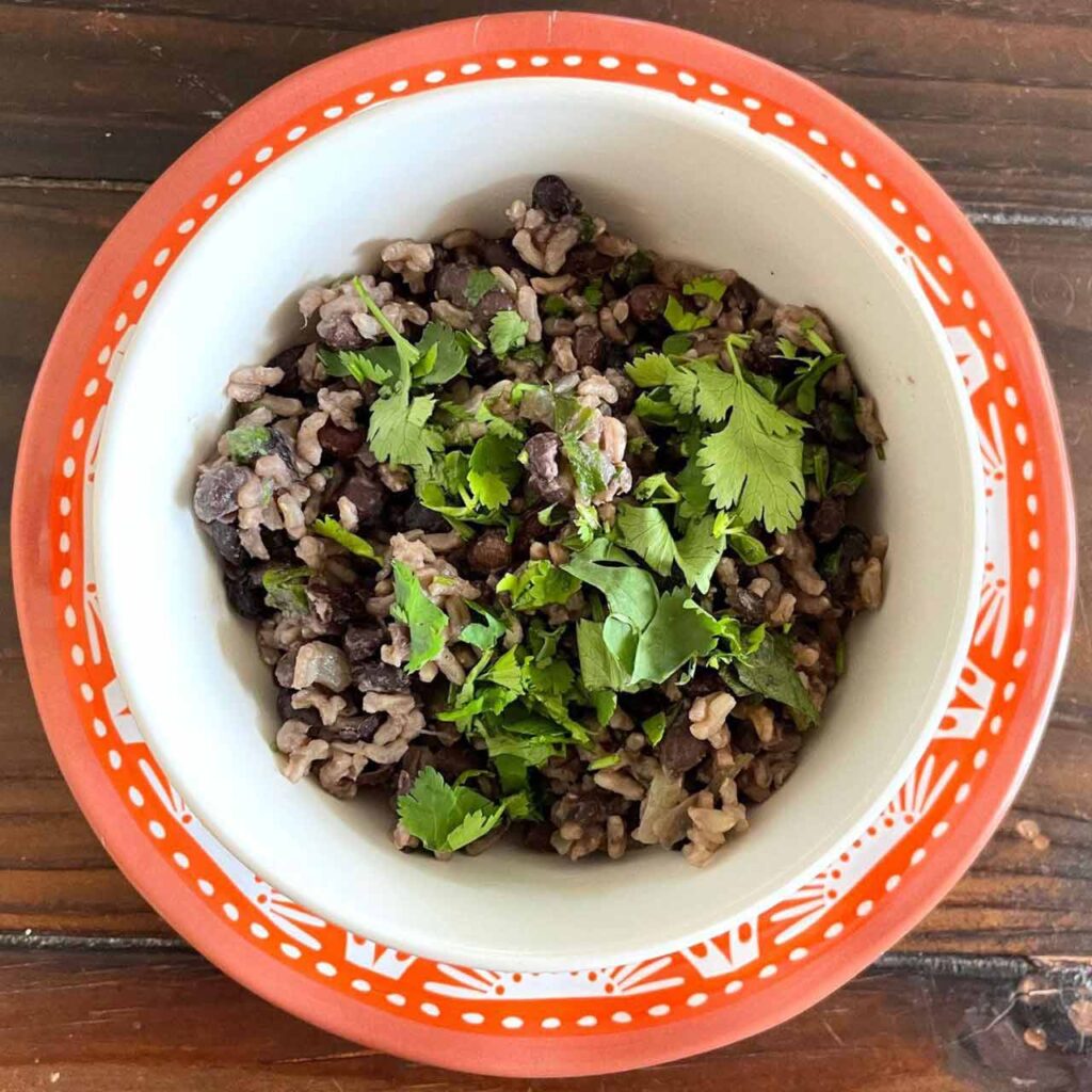Gallo pinto in a decorative bowl on a wood table.